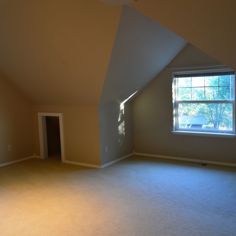 Vaulted bonus room with dormer window and fresh carpet inside a custom home built in Trout Creek MT