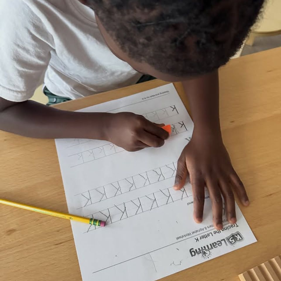 Child tracing the letter K on a handwriting worksheet during preschool language work in Palmdale CA