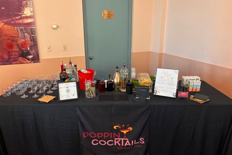 Poppin Cocktails mobile bar setup with glassware, mixers, and menu display