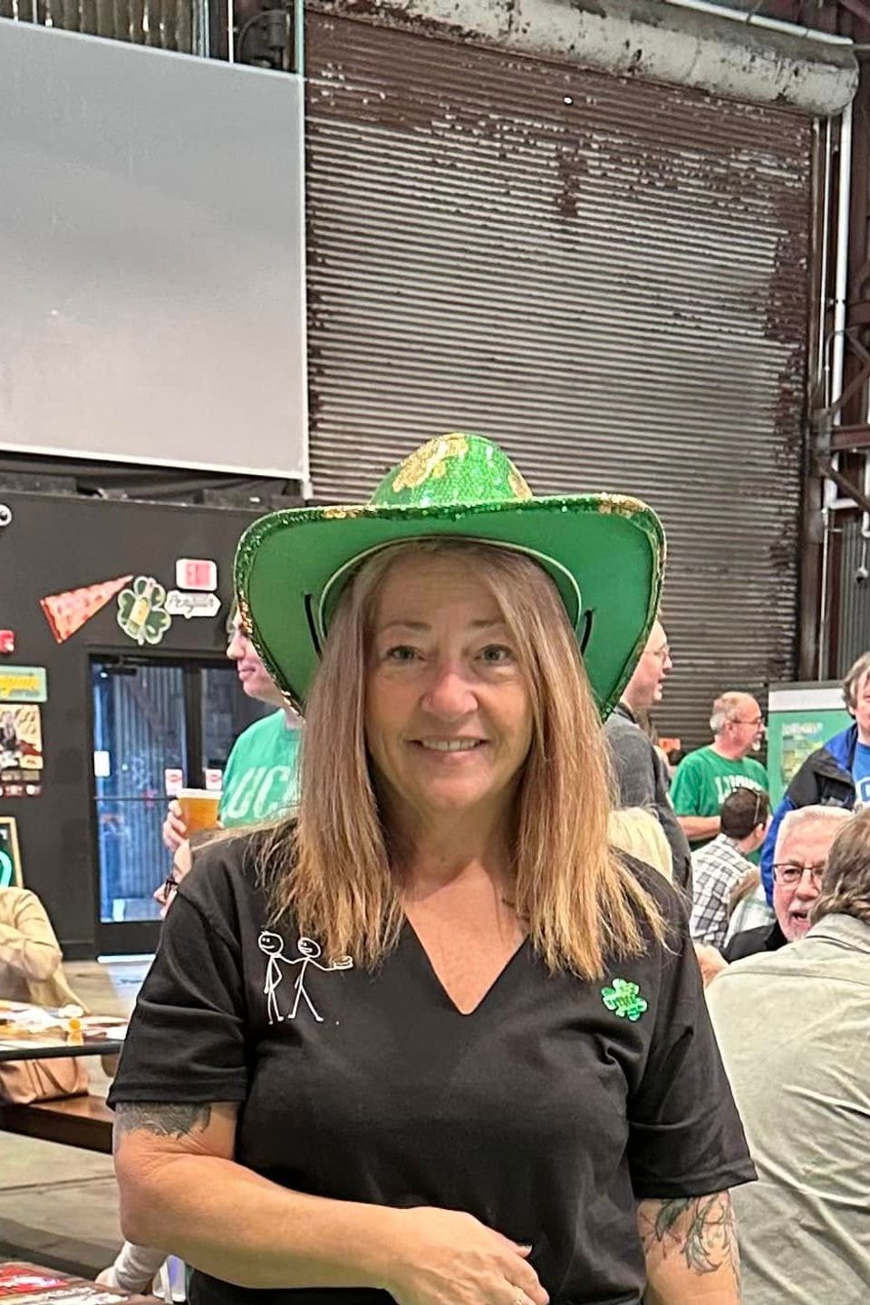 Woman wearing a green St. Patrick’s Day hat and black shirt at an indoor celebration.