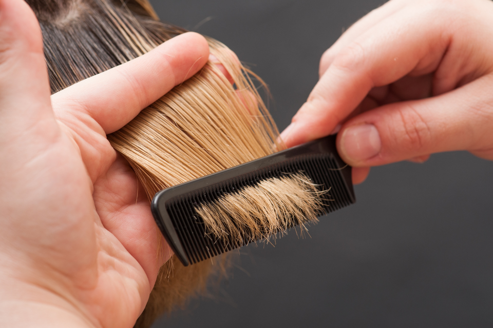 Close-up of a stylist gently combing and maintaining a wig to keep the hair smooth, healthy-looking, and tangle-free.