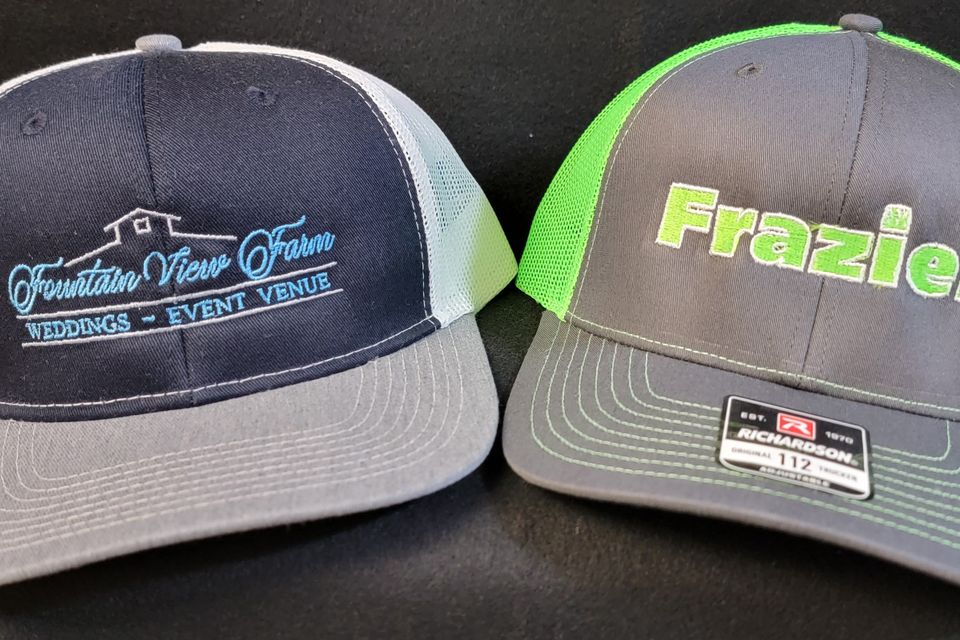 embroidery example - company logos on gray and green baseball caps