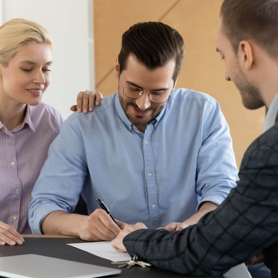 Couple signing document with insurance agent