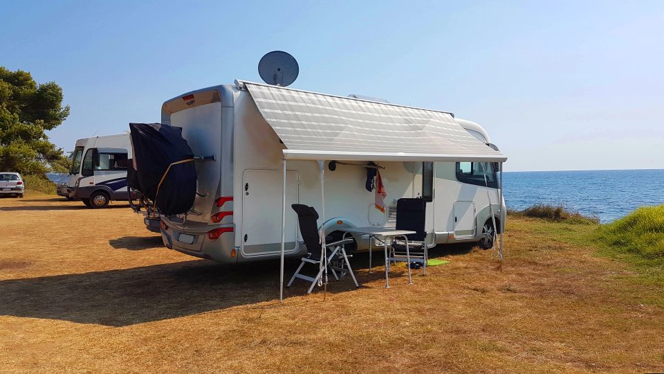 A RV parked in front of the ocean on a sunny day