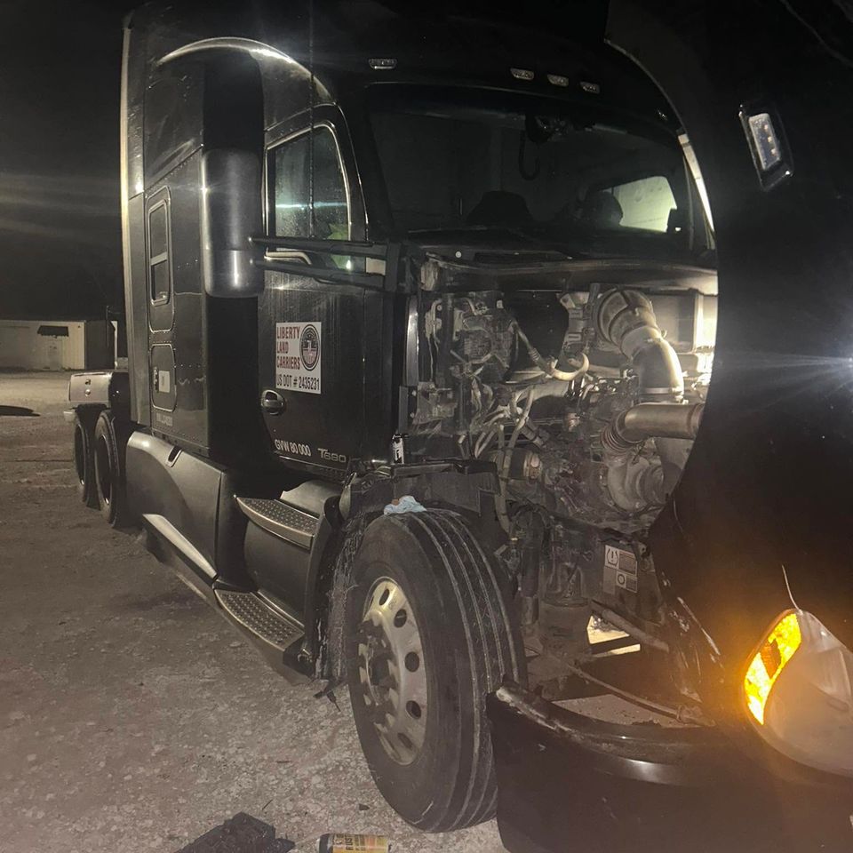 Black Kenworth T680 semi-truck with hood open for diesel engine repair at night in Arab Alabama