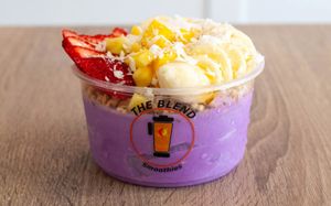 Ube Awesome bowl with ube base, strawberries, banana, mango, granola, coconut, and honey drizzle.
