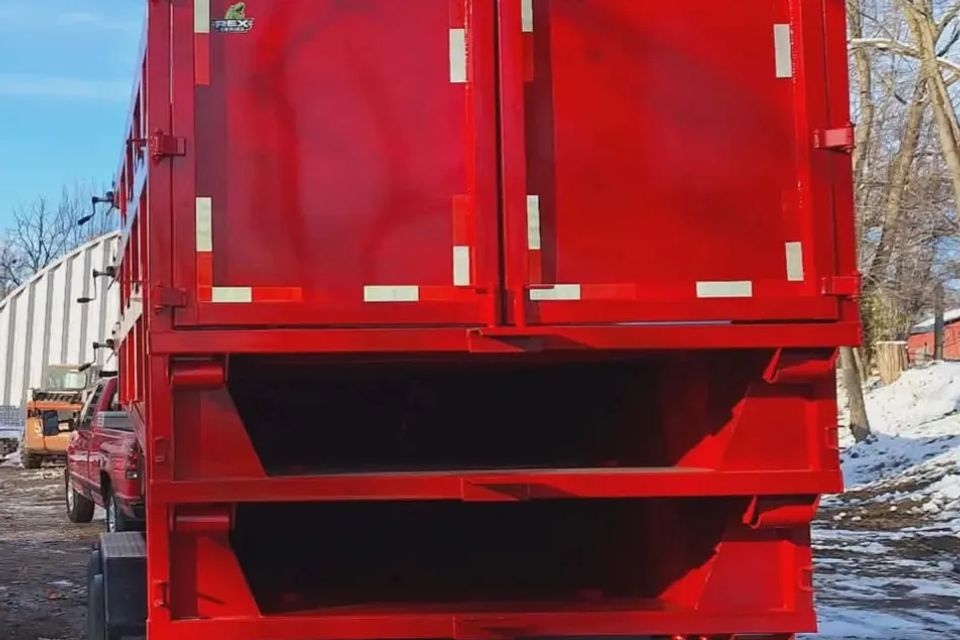 Rear view of a red Rent-A-Man Dumpster Rentals dumpster on a trailer.