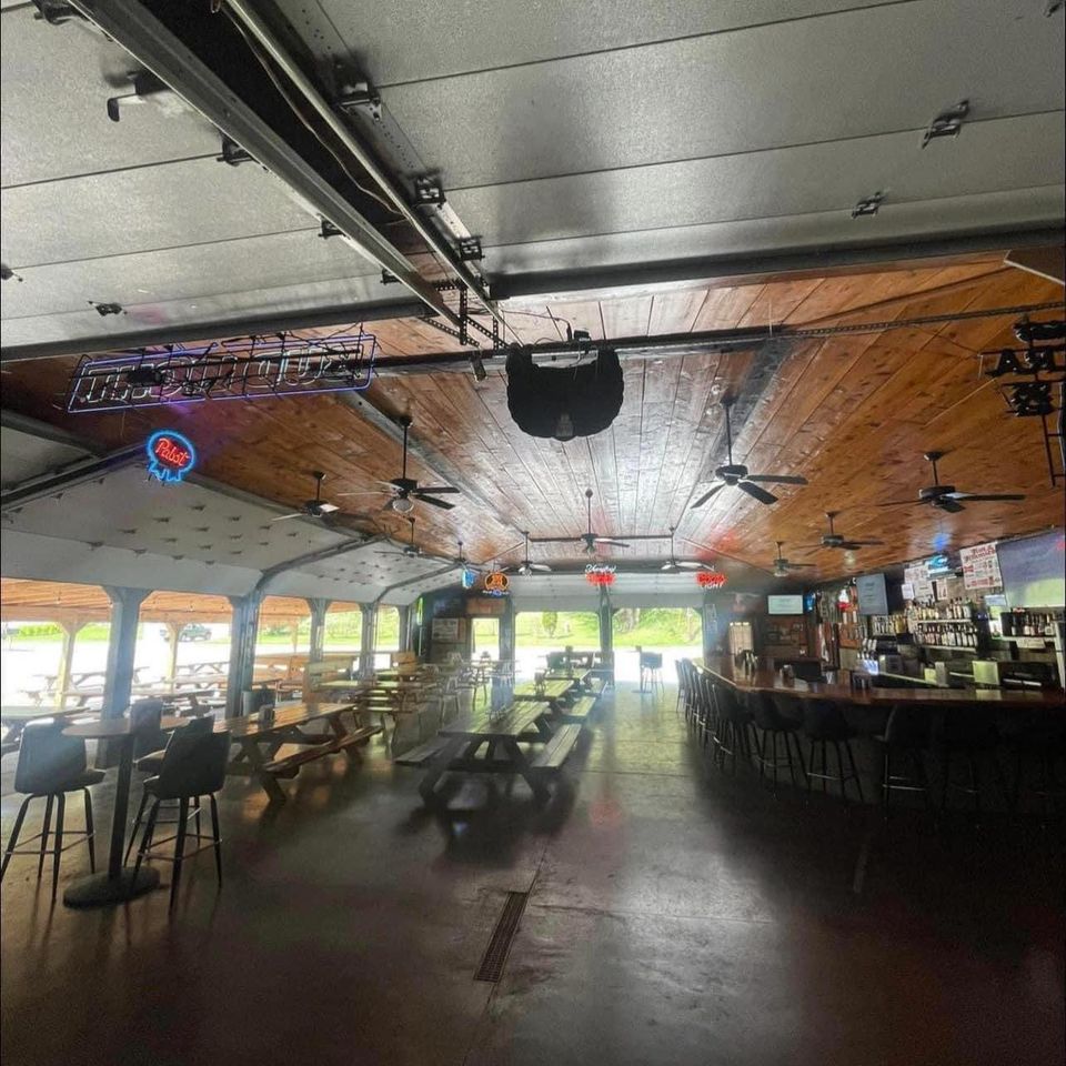 Interior view of a large tavern event space with tables, seating, and a bar area.