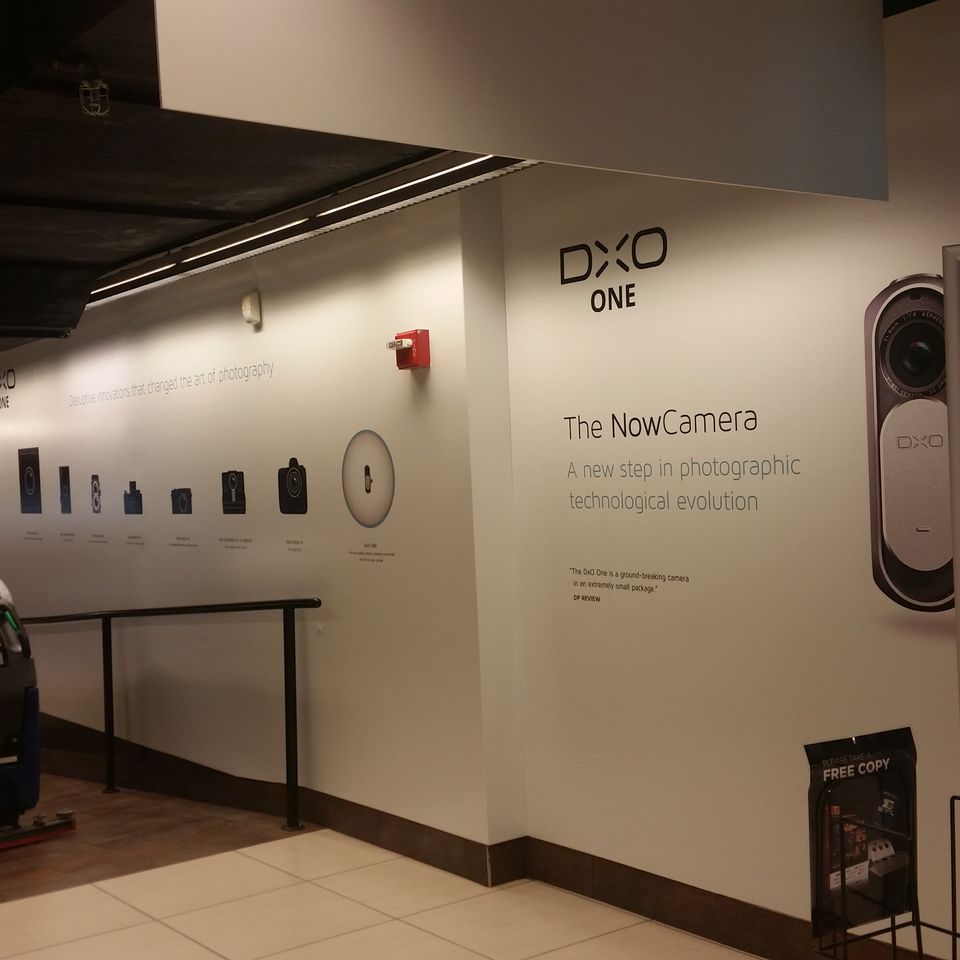 Printed wall graphics running the length of a retail interior wall with a product logo, an image timeline and a large product panel