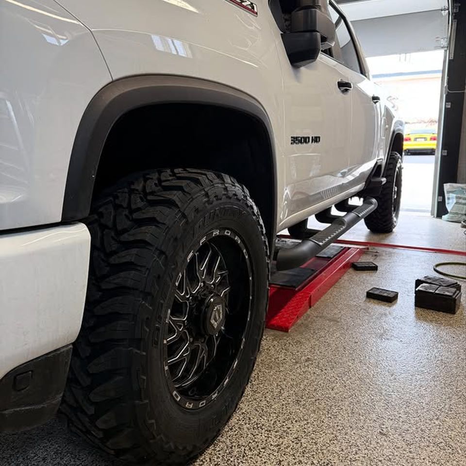 White Chevy Silverado 3500 HD with new black off-road wheels and mud tires in Claymont DE