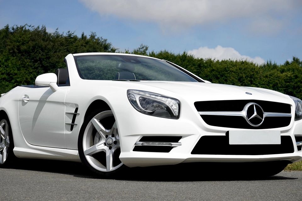 Image of a white Mercedes Benz convertible front passenger side view with front wheels turned to the right