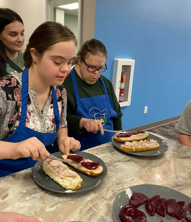 Participants with Down syndrome preparing sandwiches together during a DSAV Cooks class.