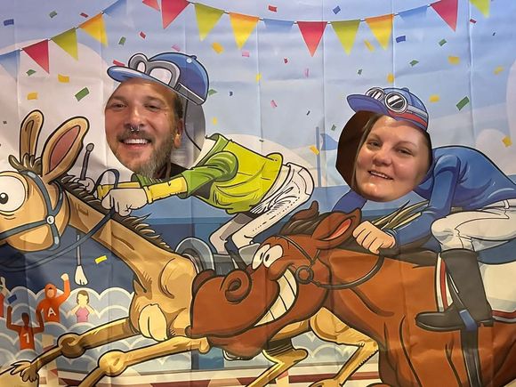 Two guests posing as jockeys in a Kentucky Derby-themed photo booth at JR's 2025 event.