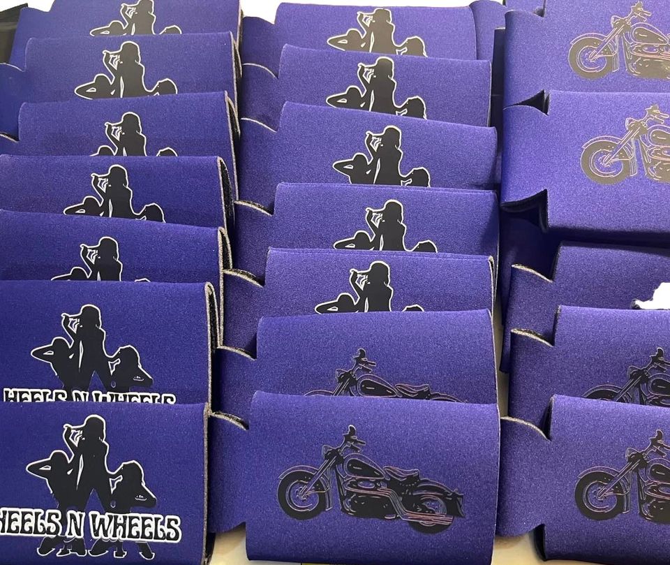 Purple beverage koozies displaying Heels 'n Wheels and motorcycle-themed logos arranged in rows.