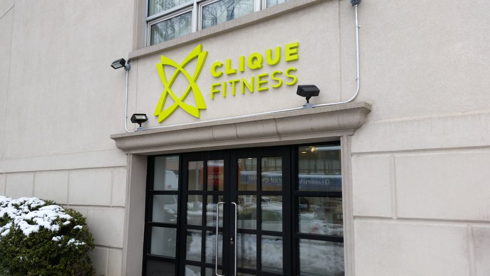 Lime green dimensional letters and a matching logo mounted on a limestone storefront above a glass entrance