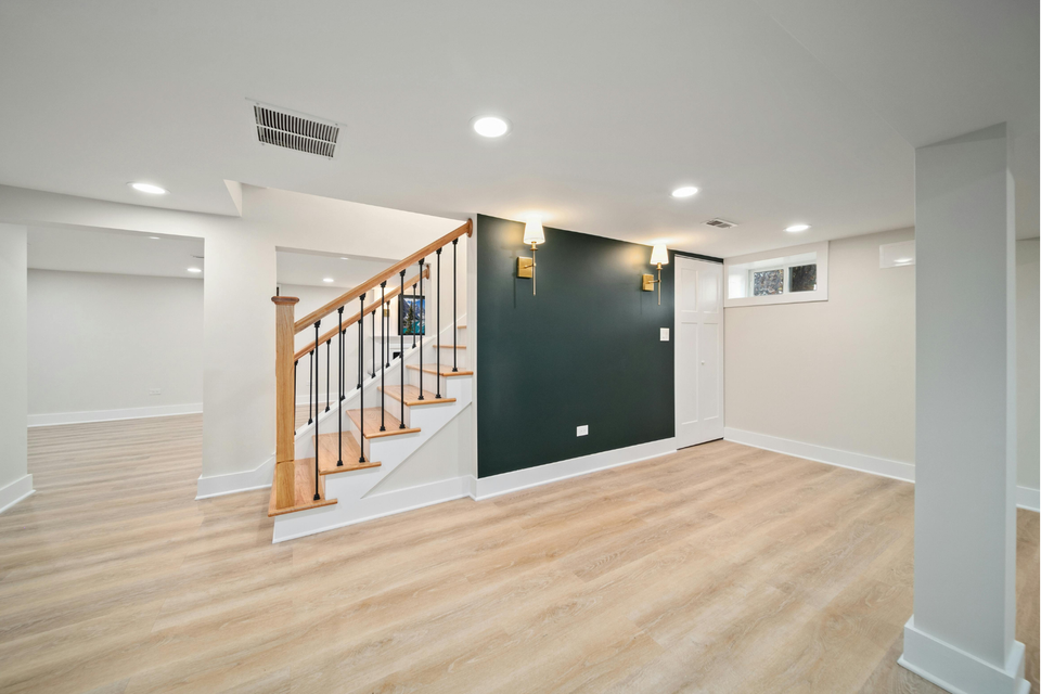 Finished basement featuring wood-look flooring, recessed lighting, painted walls, and a staircase with wood and black metal railing.