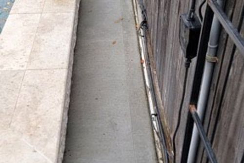 New concrete channel poured between pool deck and fence in Tomball, TX
