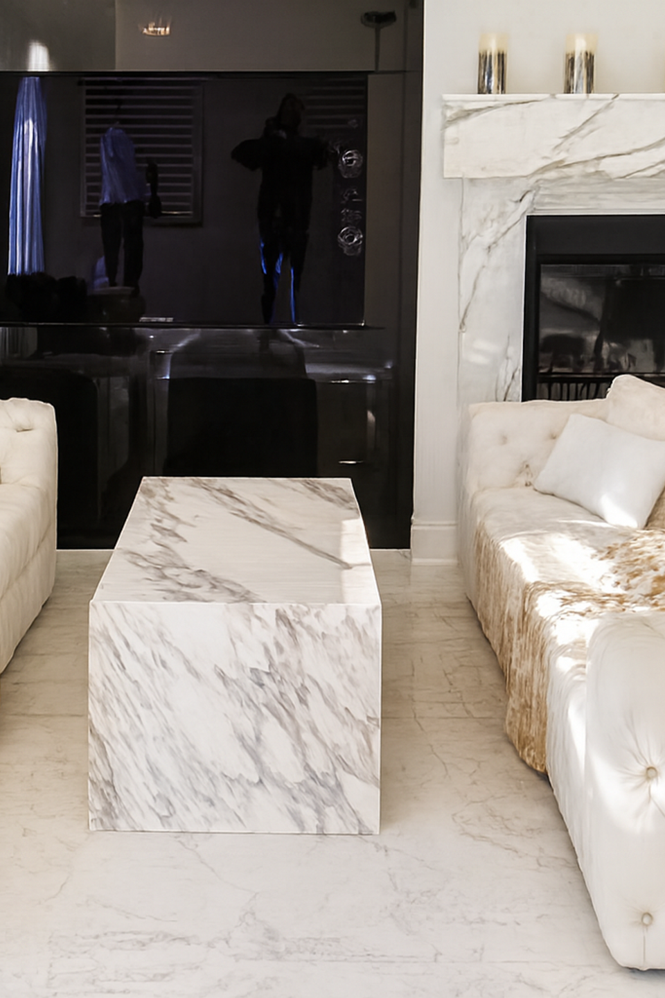 Luxurious living room with white tufted sofas and marble fireplace