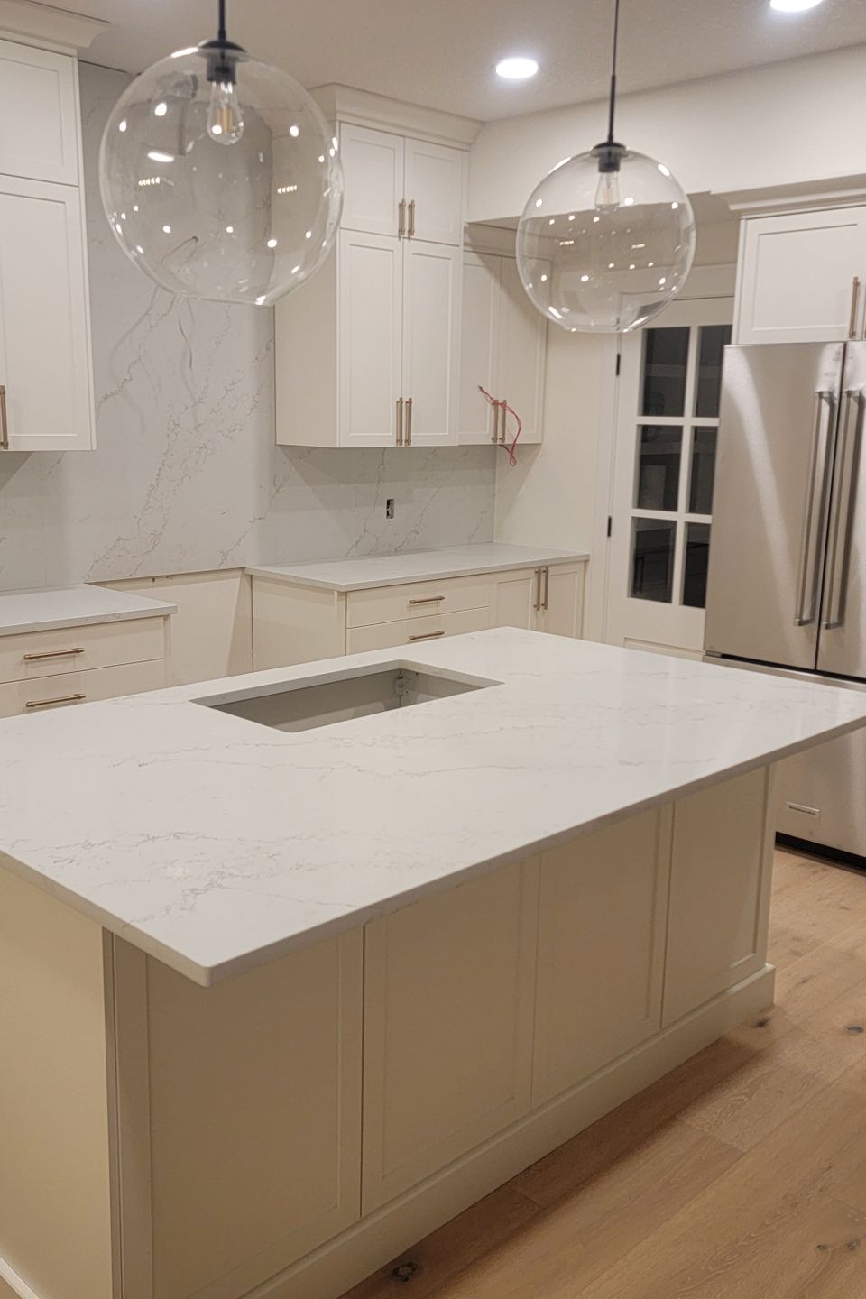 White countertop matching cupboards and stylish round light and metallic refrigerator