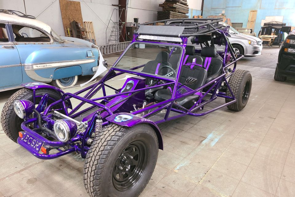 Custom-built off-road vehicle receiving specialty auto glass installation in a professional shop.
