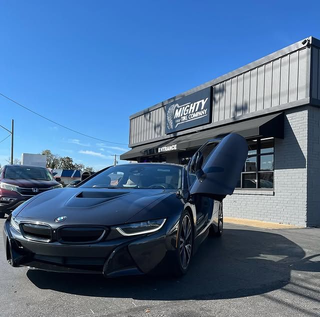 Black BMW i8 with door open parked outside Mighty Tire Company storefront in Claymont DE