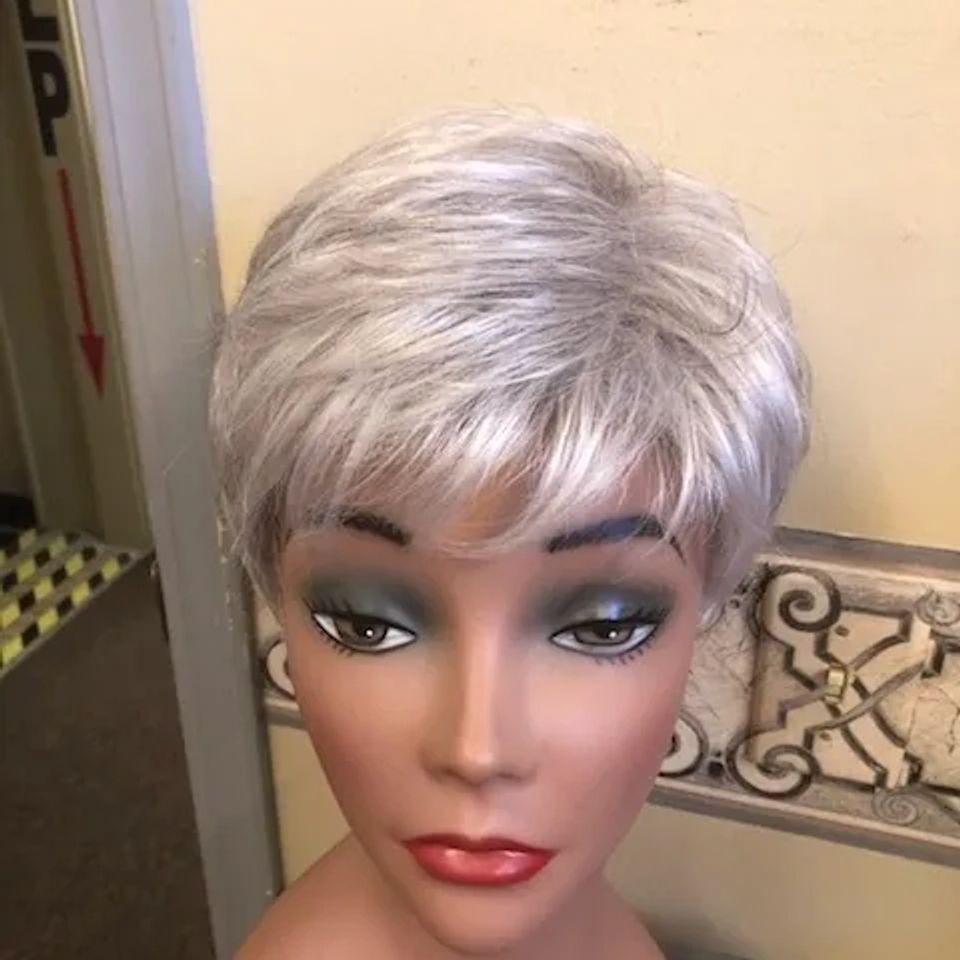 Short silver pixie-style wig with soft layers and side-swept bangs displayed on a mannequin at Shears Wigs & Hairpieces Salon.