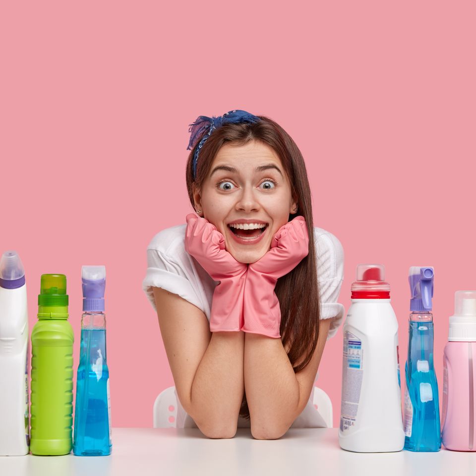 Happy young caucasian woman holds chin wears rubber protective gloves headband smiles broadly