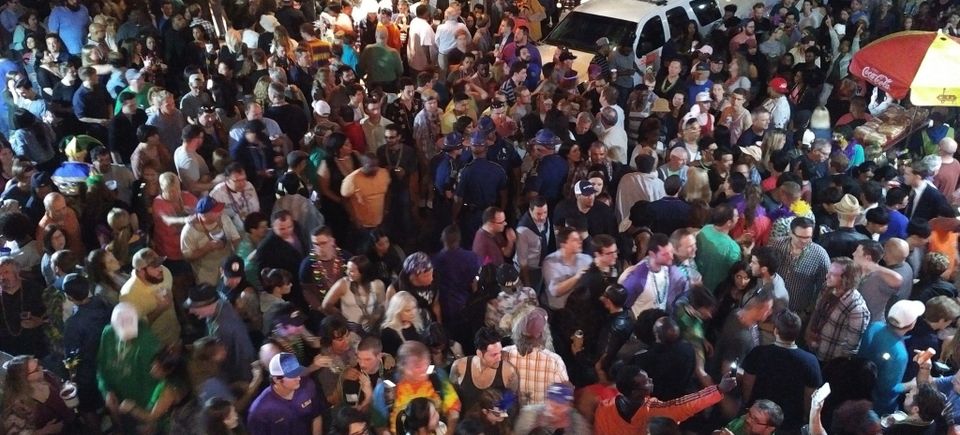 Massive Mardi Gras crowd on Bourbon Street seen from a Carpe Diem Events VIP balcony during the celebration