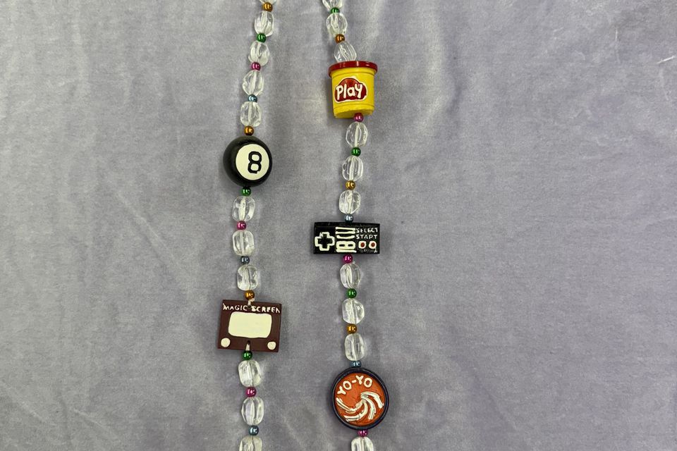 Retro toy beads with symbols from the 80's including Play-Doh and magic eight ball.