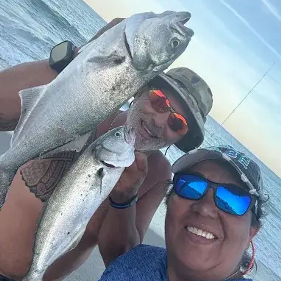 Couple holding fish at the beach