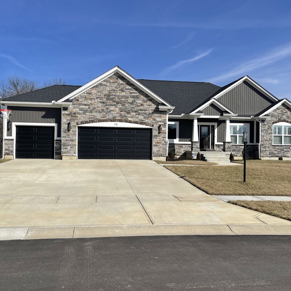 Stone-front home with a professionally installed dark gray architectural asphalt shingle roof by E & D Roofing, Inc.