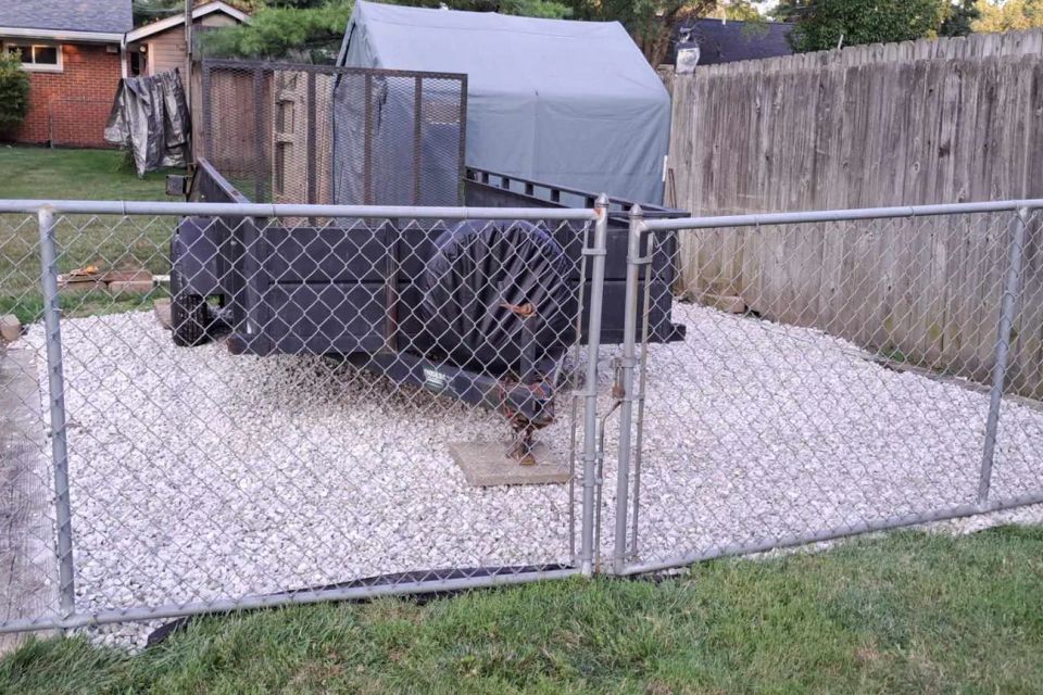White gravel installed around backyard utility equipment inside a fenced area.