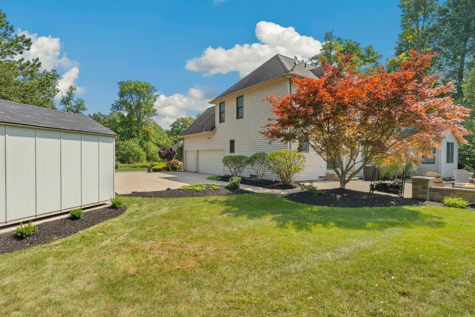 Well-maintained residential property with a manicured lawn, fresh mulch beds, ornamental trees, and neatly trimmed shrubs maintained by R.E.P. Companies.