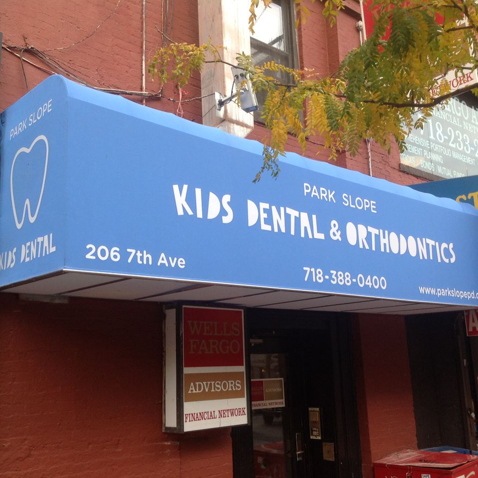 Bright blue custom storefront awning with a printed tooth logo and lettering on a Park Slope dental office in Brooklyn