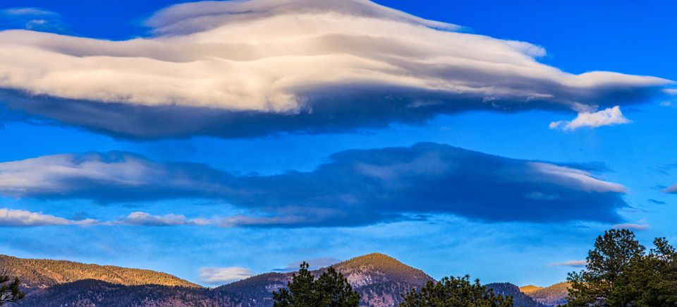 Sunset lenticular clouds over the wet mountains