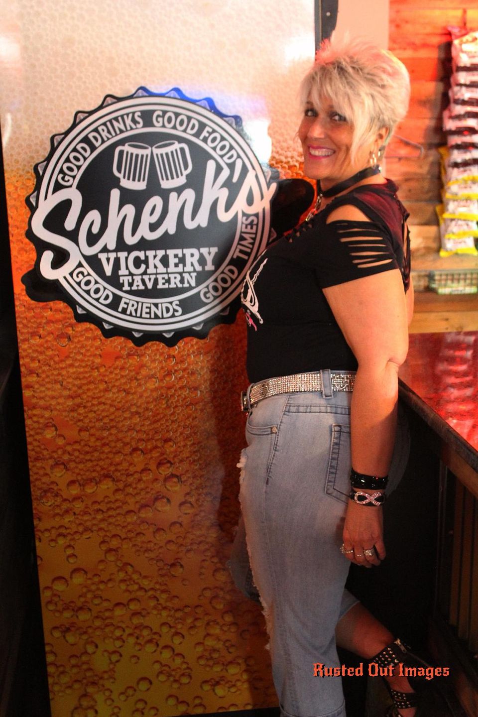 Kelly smiling beside the Schenky’s Victory Tavern sign during a social event.