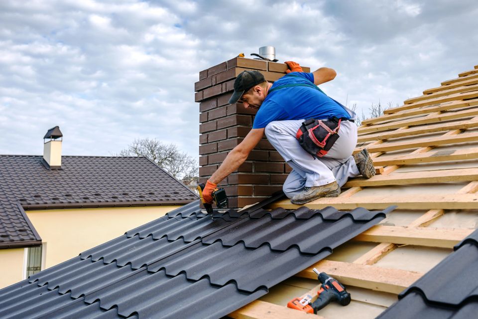 A roofer with an electric screwdriver covers repairs the roof