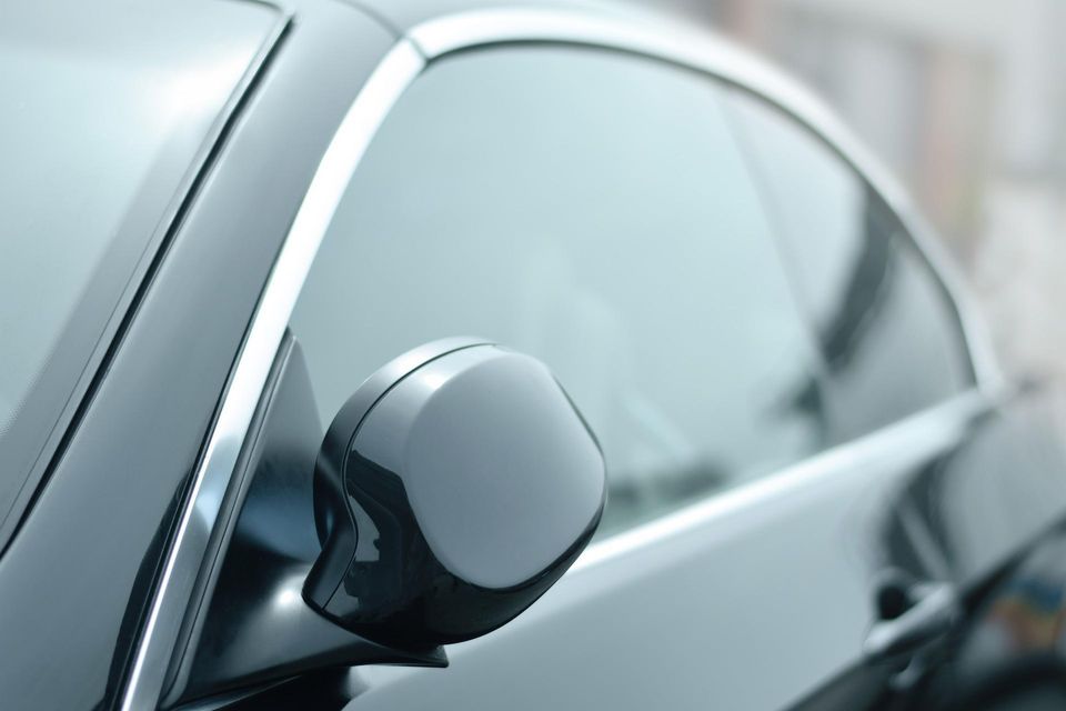 Close-up of a vehicle side mirror and window representing insurance-covered auto glass repair and replacement services.