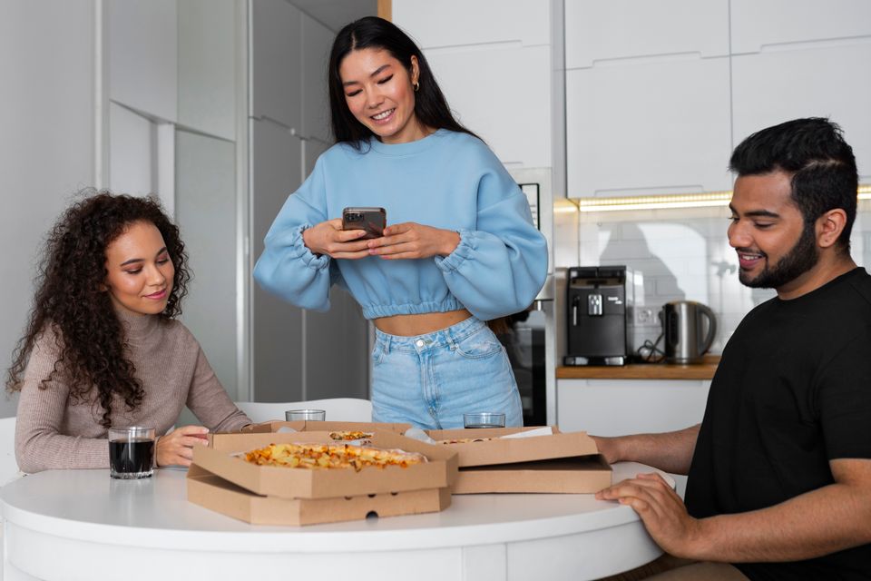 Friends taking pictures while eating pizza home