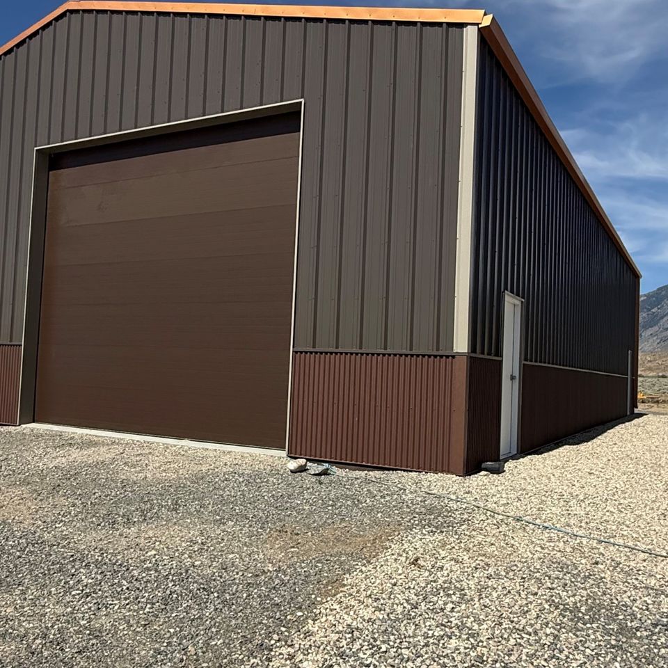 Brown metal building exterior with tall overhead garage door built in Trout Creek Montana