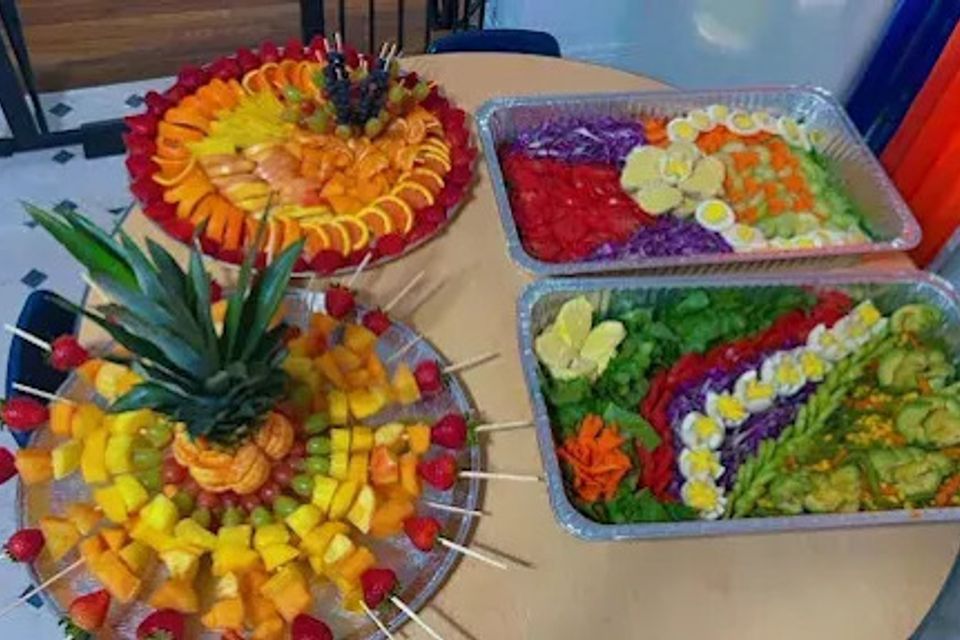 African catering spread with layered vegetable salad trays and pineapple fruit platter for a Los Angeles CA event