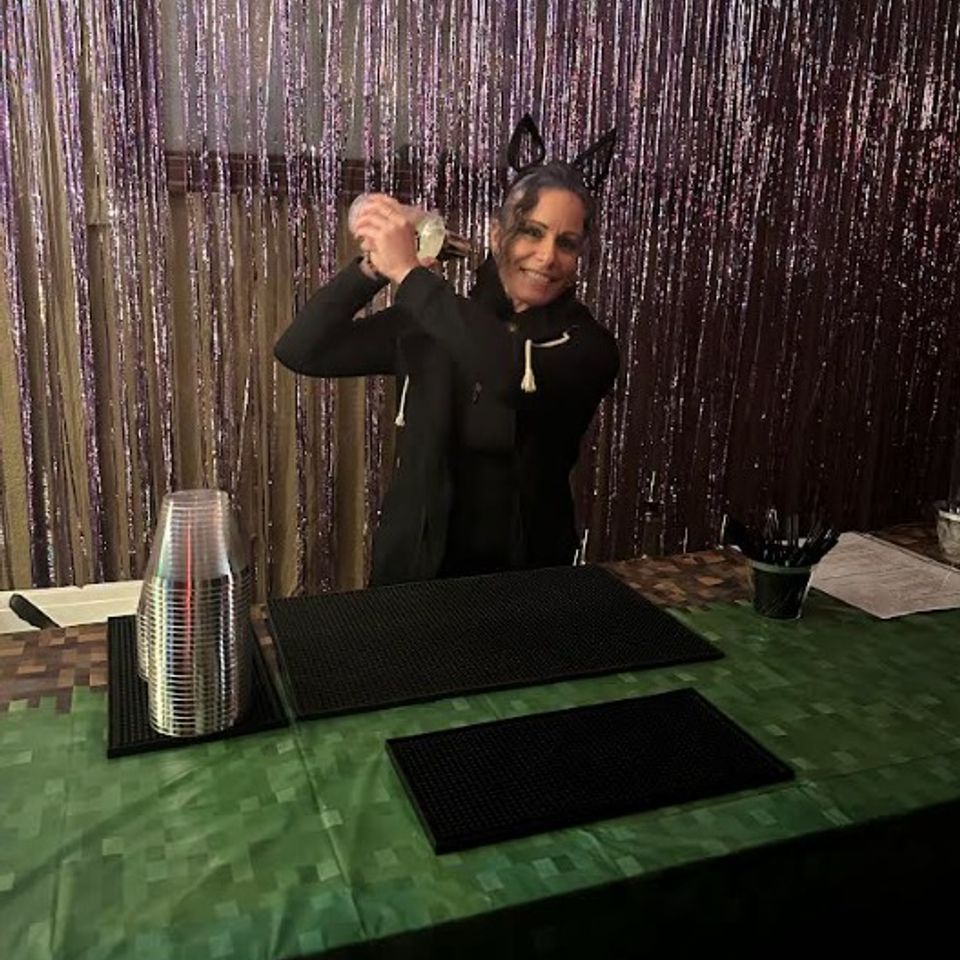 Full bar setup with the owner mixing drinks and halloween backdrop decor