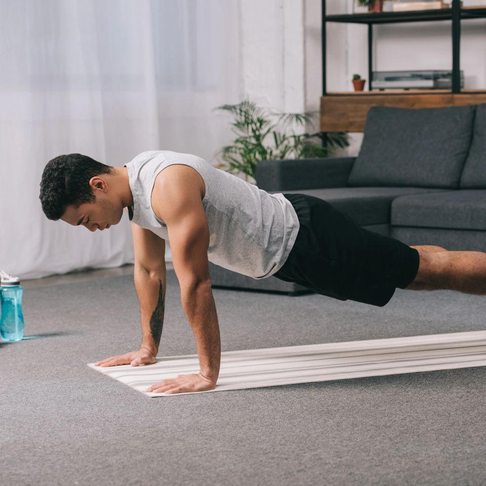 Man holding a push up plank on a mat during an in-home workout