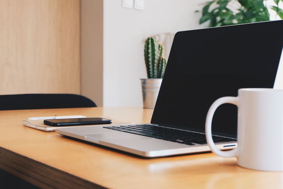 Desk with cell phone, laptop and coffee cup