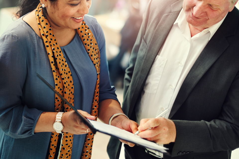 Woman holding a petition and man signing.