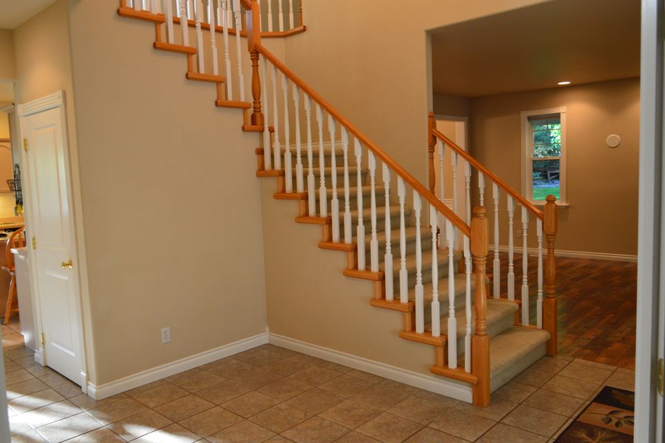 Carpeted staircase with stained oak handrail and white turned balusters in a custom home