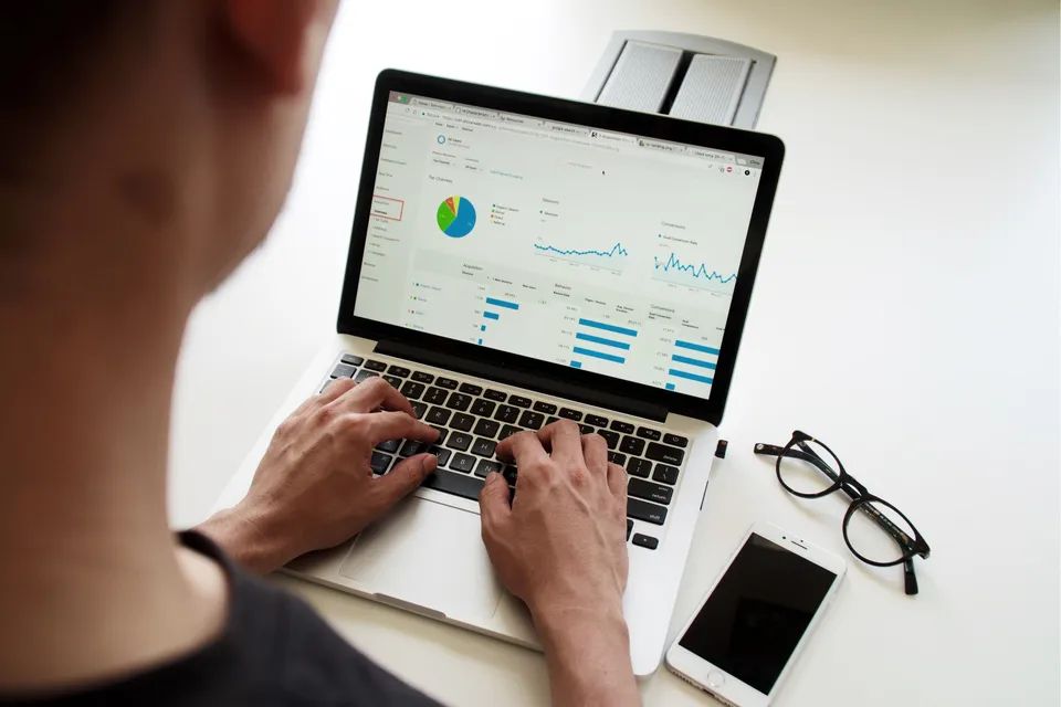 Man with laptop typing while screen displays some website traffic statistics