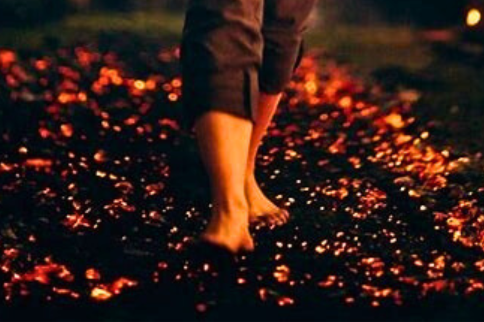 close-up of bare feet stepping onto hot embers in a firewalking challenge
