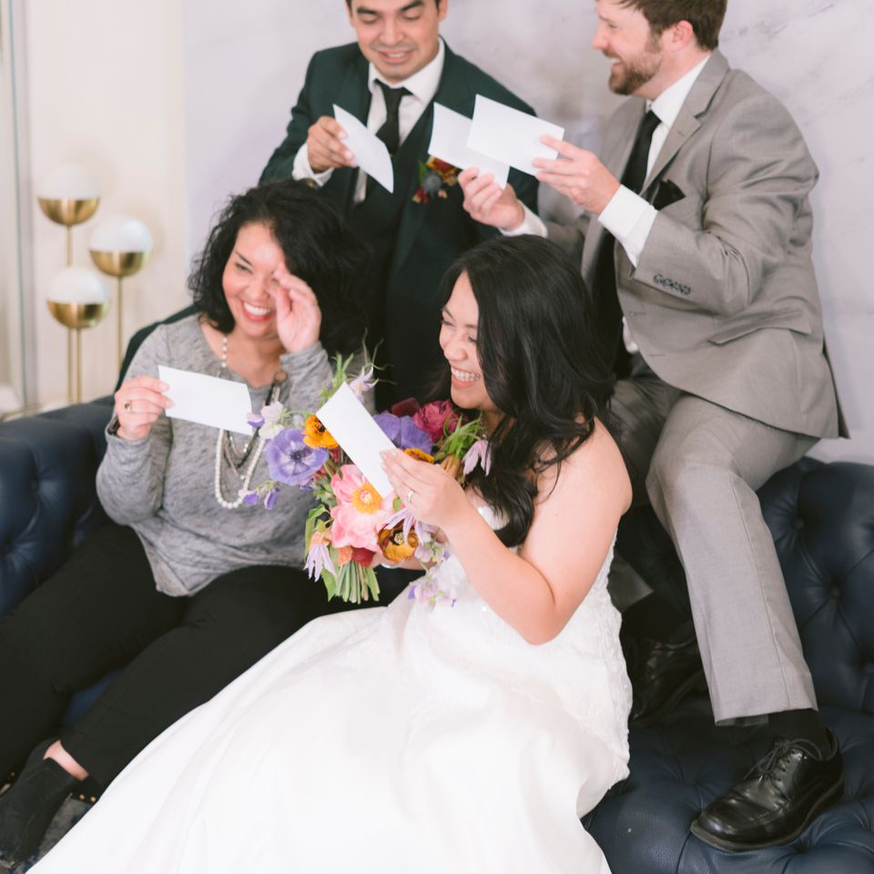 Wedding guests and bride smiling while looking at printed photo booth pictures