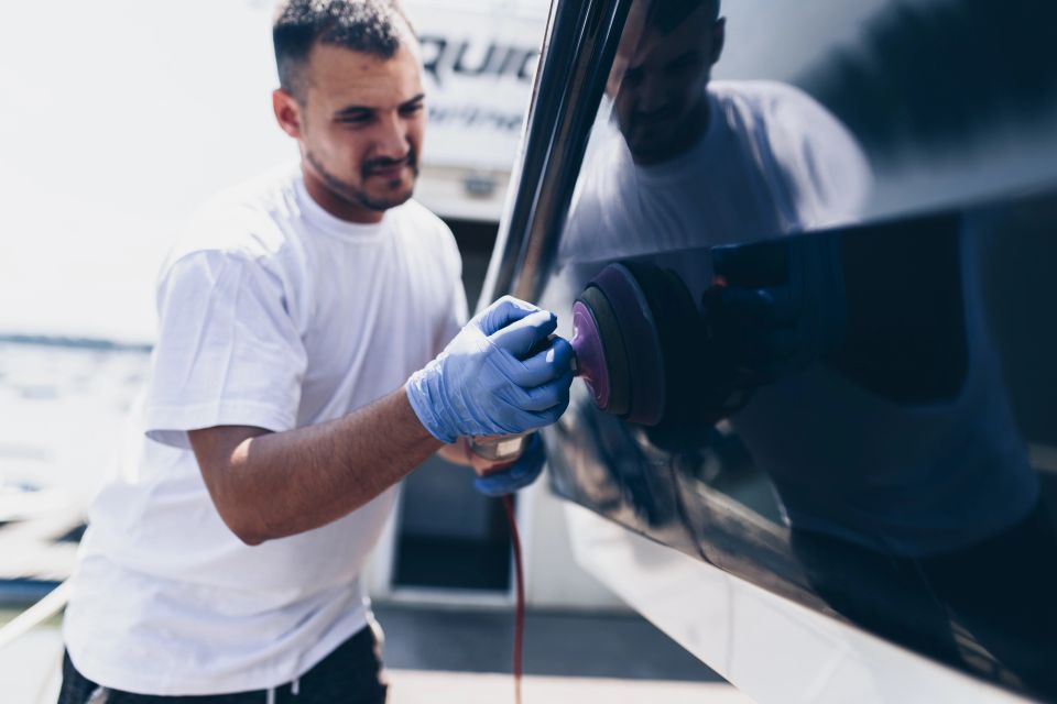 Detailer using an orbital polisher on a glossy boat hull during marine detailing